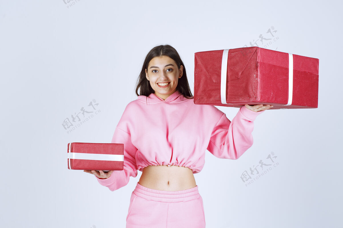 员工穿着粉色睡衣的女孩拿着大大小小的红色礼盒 微笑着员工庆祝服装