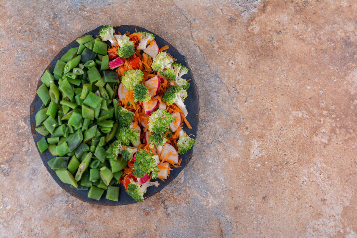 健康一小盘混合蔬菜沙拉和切碎的豆荚放在大理石表面豆类豆类萝卜
