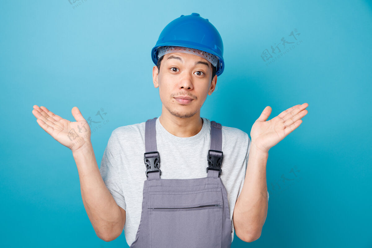空无知的年轻建筑工人戴着安全帽 穿着制服 两手空空的穿手头盔
