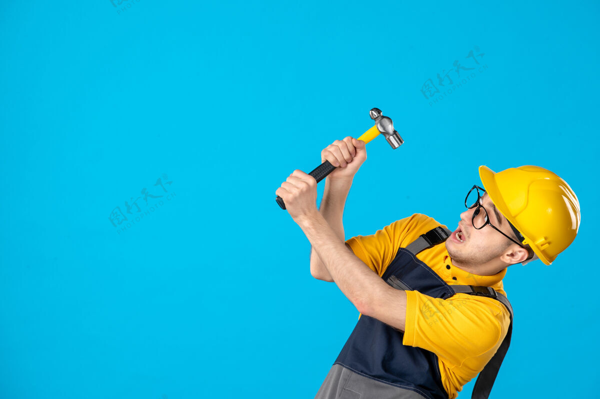 男工人穿着黄色制服的男工人的正视图 锤子放在蓝色制服上锤子表面服务
