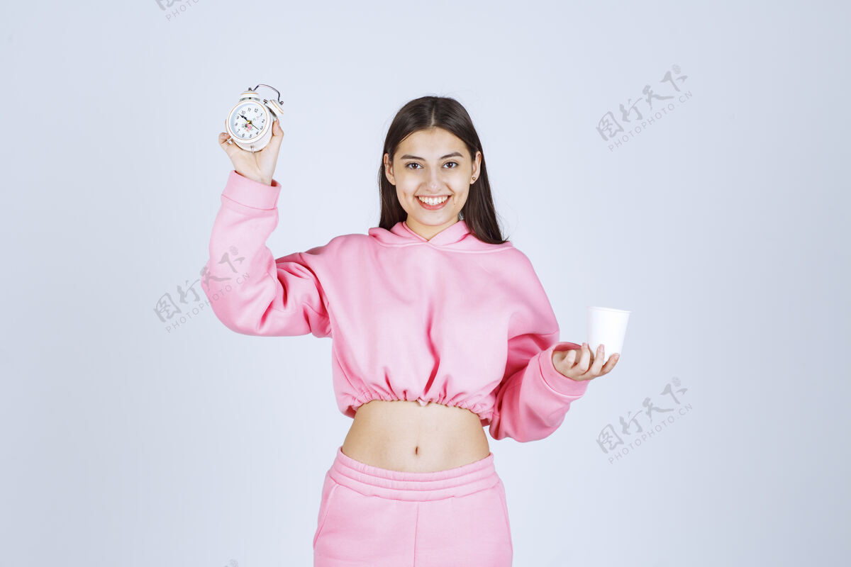 人类穿着粉色睡衣的女孩手里拿着闹钟和一杯咖啡姿势常规女性
