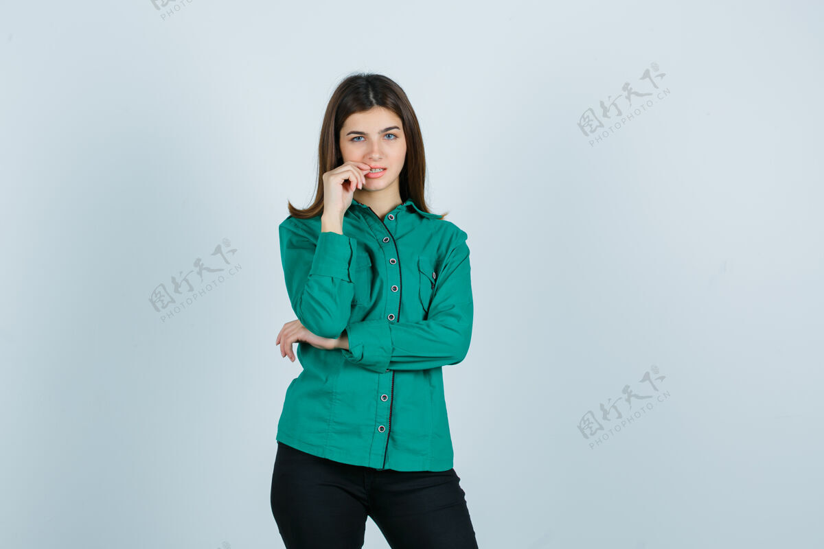 女士年轻女性咬指甲在绿色衬衫 裤子和期待沉思前视图的肖像年轻自然衬衫