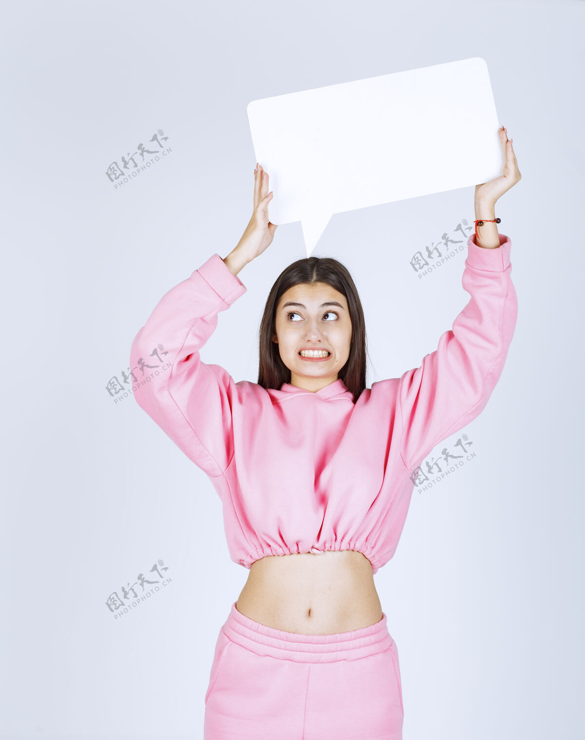 员工穿着粉色睡衣的女孩头上举着一个空白的长方形盒子在思考人体模型人头脑风暴
