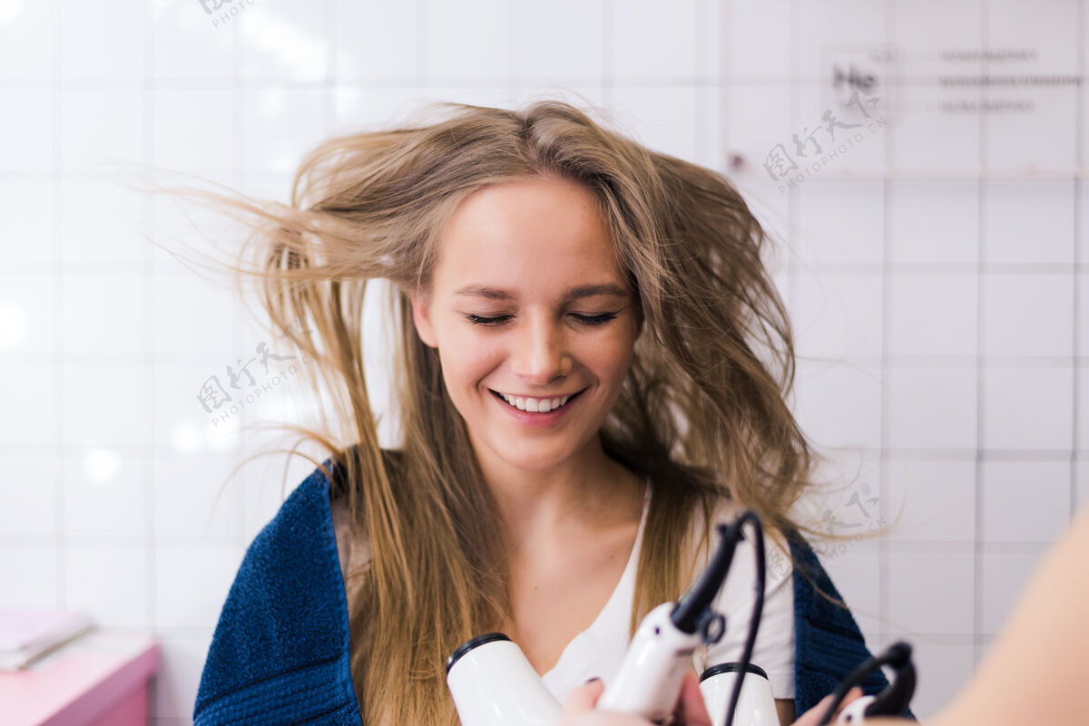 剪年轻女子美发师手里拿着吹风机发型女子美发专业美容院理发师发型师男人
