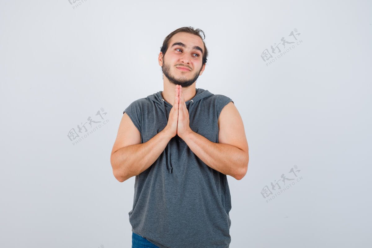 天空穿着无袖连帽衫的年轻健康男性保持双手祈祷的姿势 看起来充满希望 正面视图应用程序祈祷保持