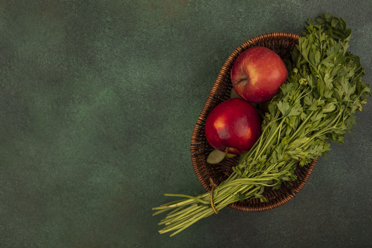 美味新鲜的红苹果和欧芹在一个绿色的表面与复制空间桶顶视图苹果特写新鲜