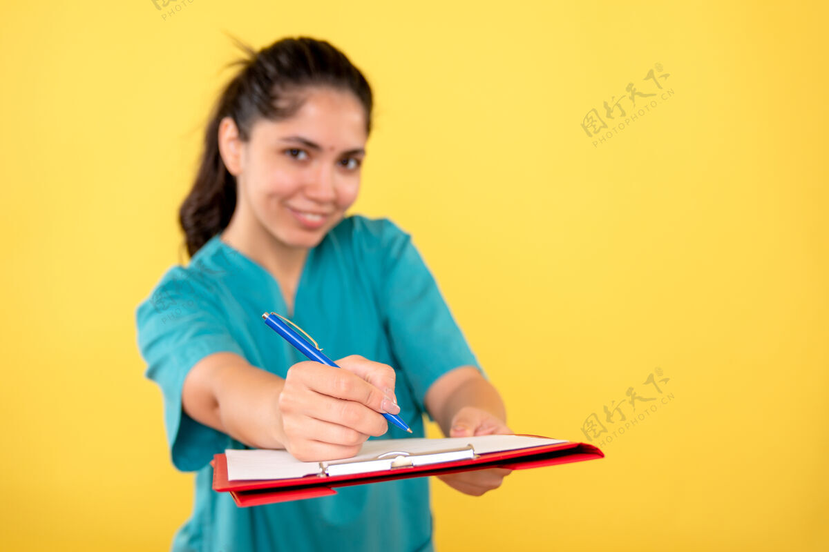 人物前视图微笑的年轻女性拿着黄色背景上的剪贴板学生漂亮商业