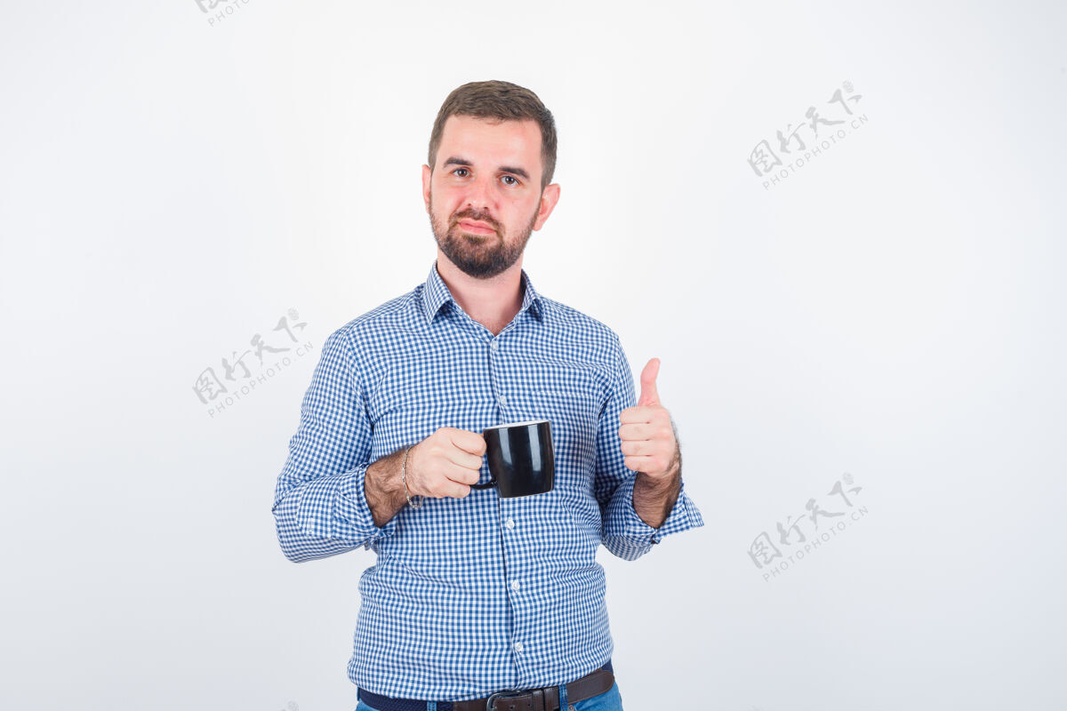 杯子穿着衬衫 牛仔裤的年轻男子举着杯子竖起大拇指 看上去很高兴 正前方表演表情前面