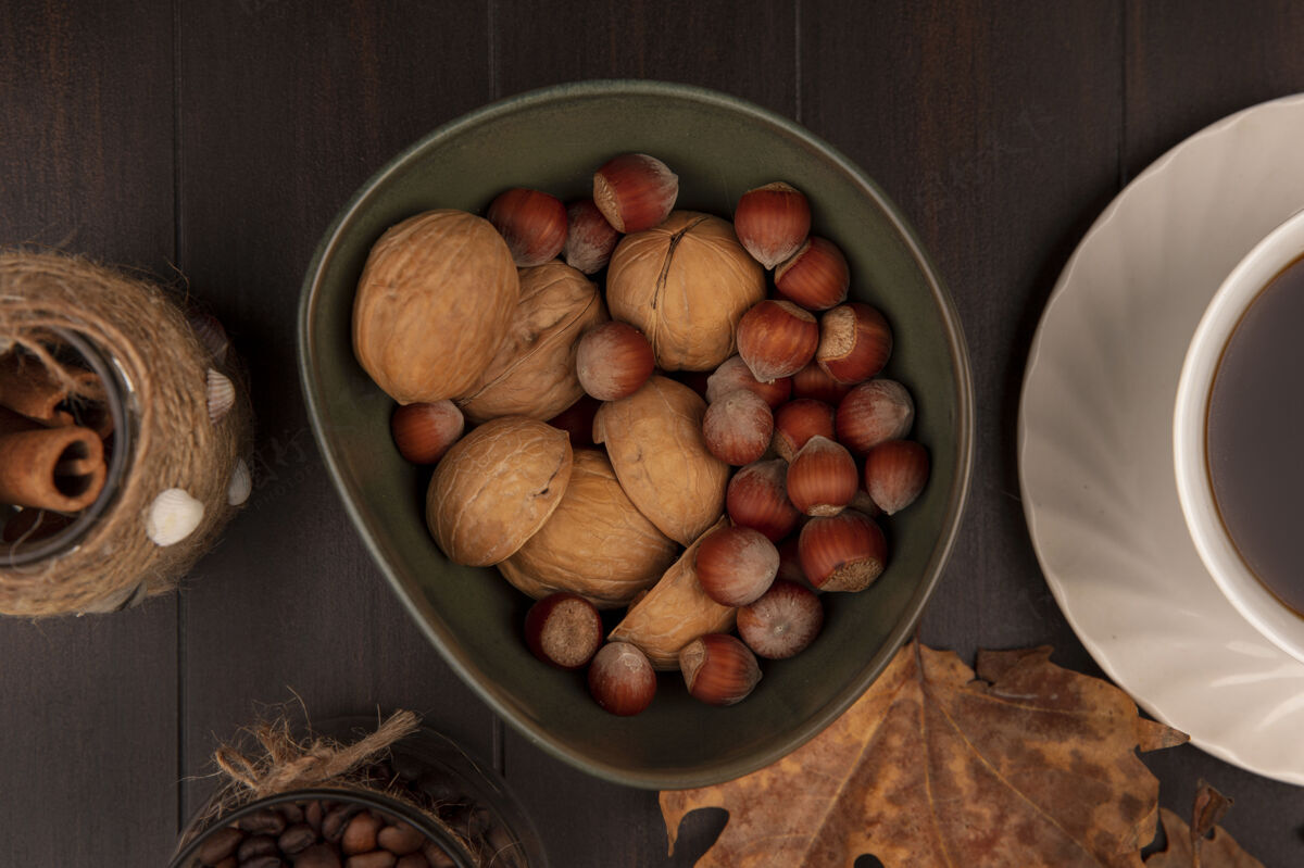 肉桂俯视图上的坚果与肉桂棒与咖啡豆在一个玻璃罐上的木制表面碗饮食种子豆类