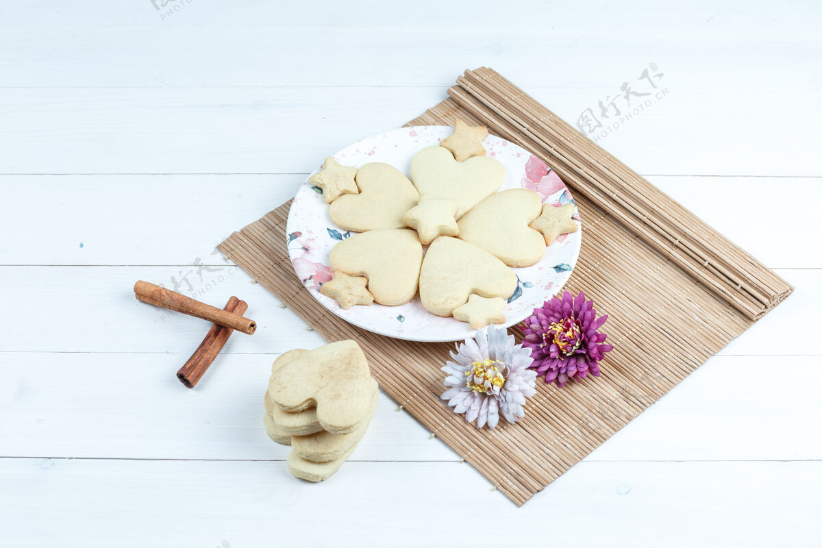 木头高角度观看心形和星形饼干 鲜花放在肉桂垫子上脆早餐自制