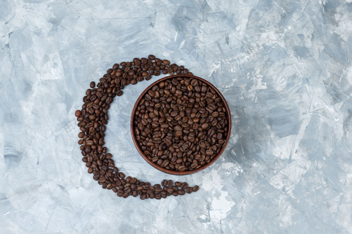 新鲜咖啡豆放在灰色灰泥背景的泥碗里顶视图美食烤豆类