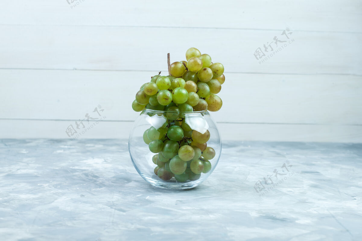 树枝绿色的葡萄在一个玻璃罐侧视图在肮脏的灰色和木制背景串甜点木头