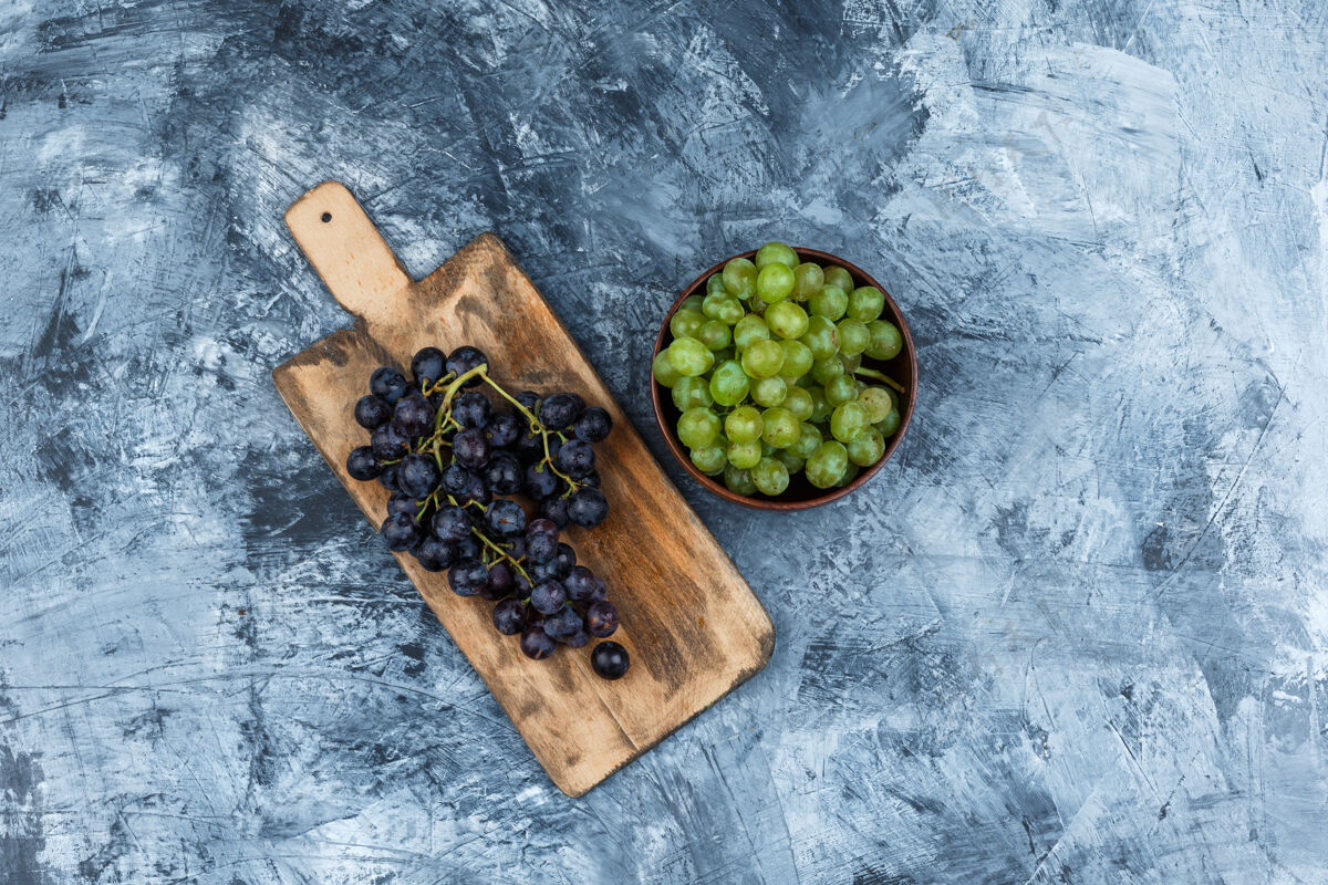 农业把黑葡萄平放在砧板上 把一碗白葡萄放在深蓝色大理石背景上水平多汁碗树枝