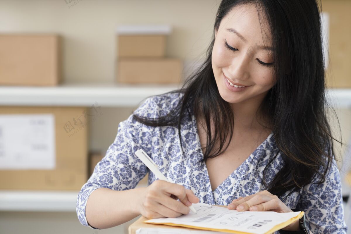 盒子特写：一个黑发的年轻女人在写包裹微笑业务工作