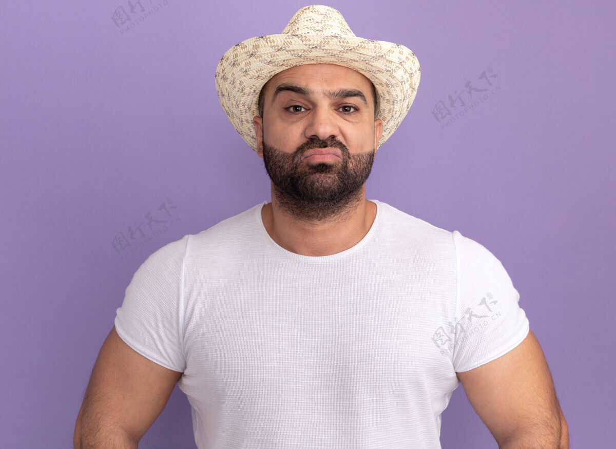 男人身穿白色t恤 头戴夏帽 表情严肃自信的大胡子男人站在紫色的墙上表情胡子立场