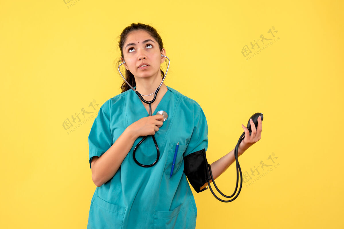 专业前视图确定女医生穿着制服 手持血压计 在黄色背景上看得很高医学护士医学