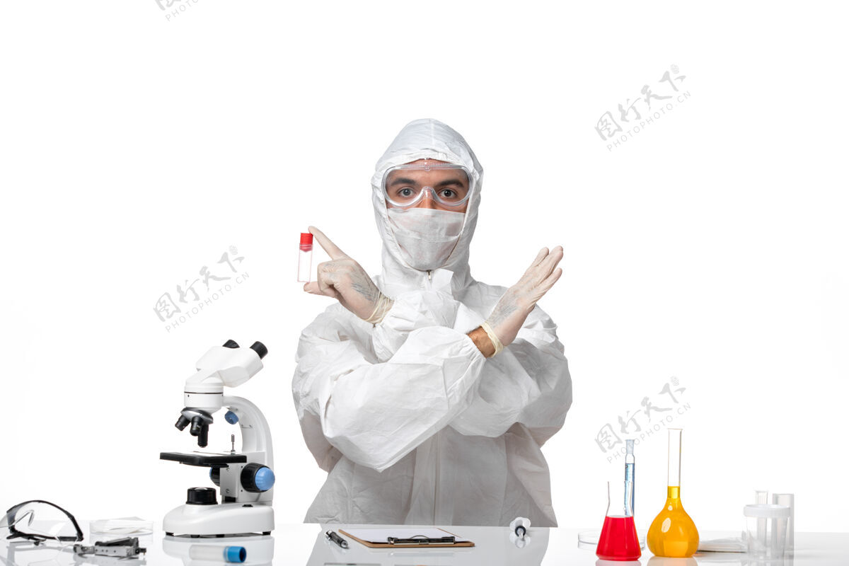 专业正面图：男医生穿着防护服 戴着口罩 因为白色桌子上有一个小瓶子病毒男医生办公桌