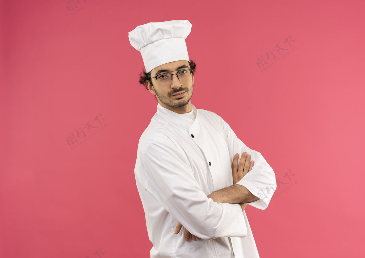 手高兴的年轻男厨师穿着厨师制服和眼镜交叉手请男烹饪