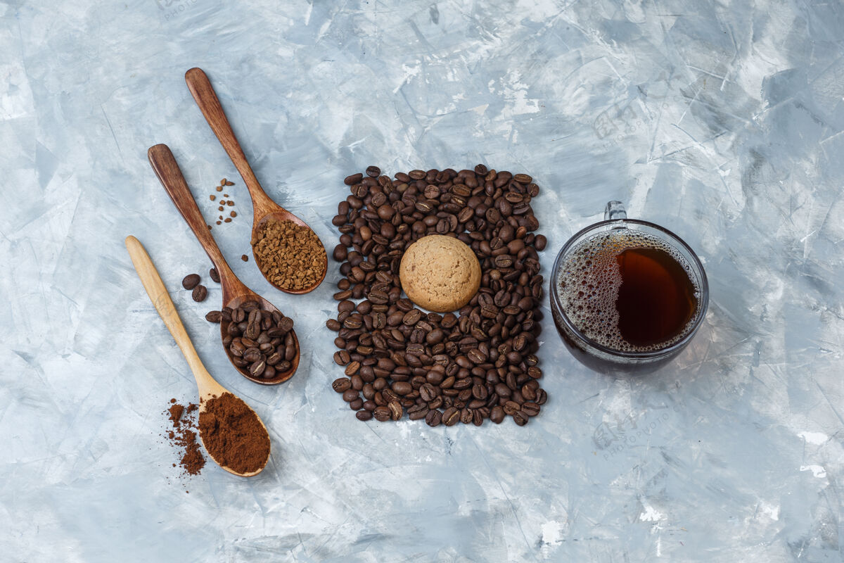 拿铁特写咖啡豆 一杯咖啡加咖啡豆 速溶咖啡 咖啡粉装在木勺里 浅蓝色大理石背景上的饼干水平乐趣卡布奇诺早餐