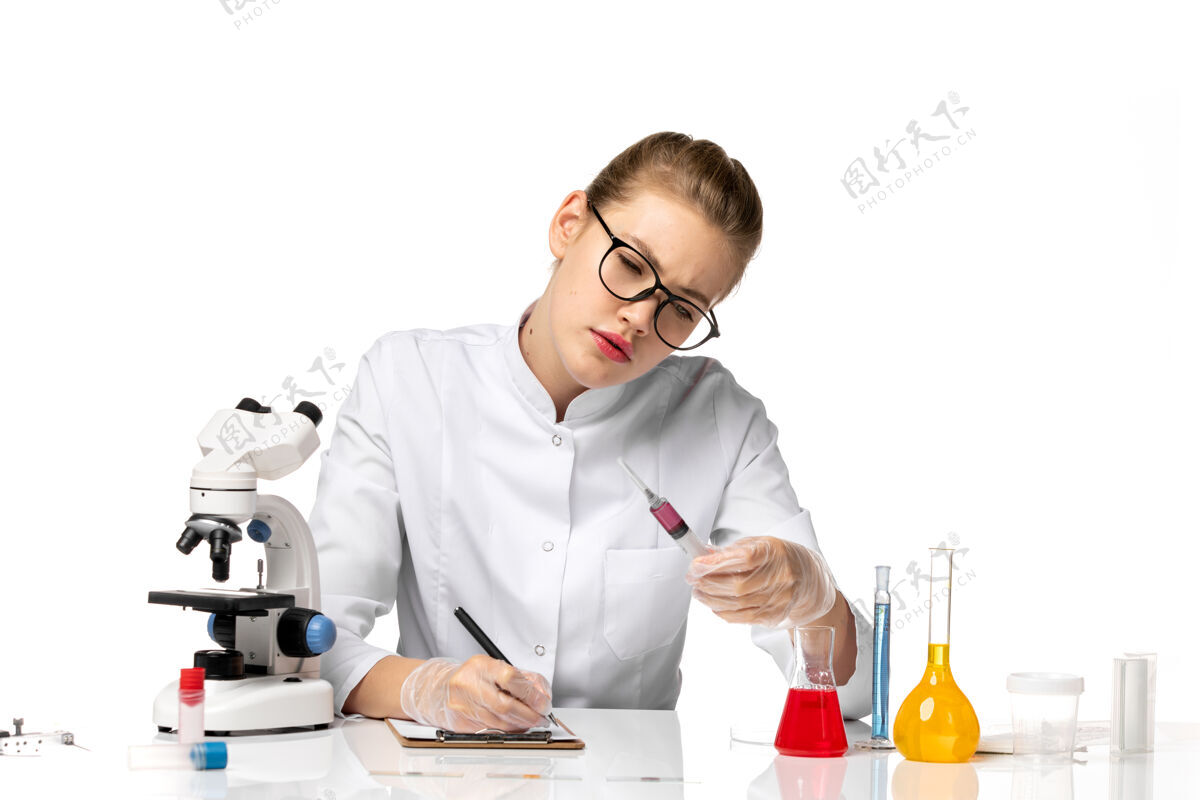 持有正面图：穿着白色医疗服的女医生在浅白的桌子上拿着针剂医生办公室女医生