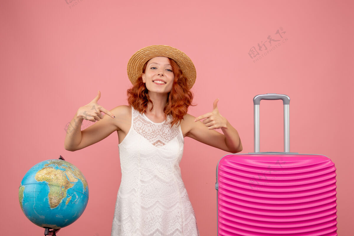 模特年轻女性游客的正面图 粉红色的墙上挂着粉红色的包前面人航行