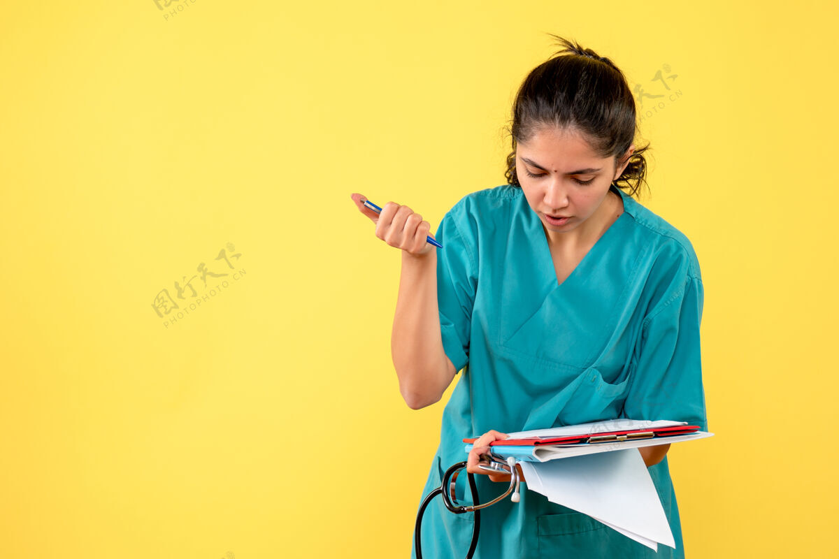 前面站在黄墙上的年轻女医生在纸上写东西的正面图年轻女医生纸随便