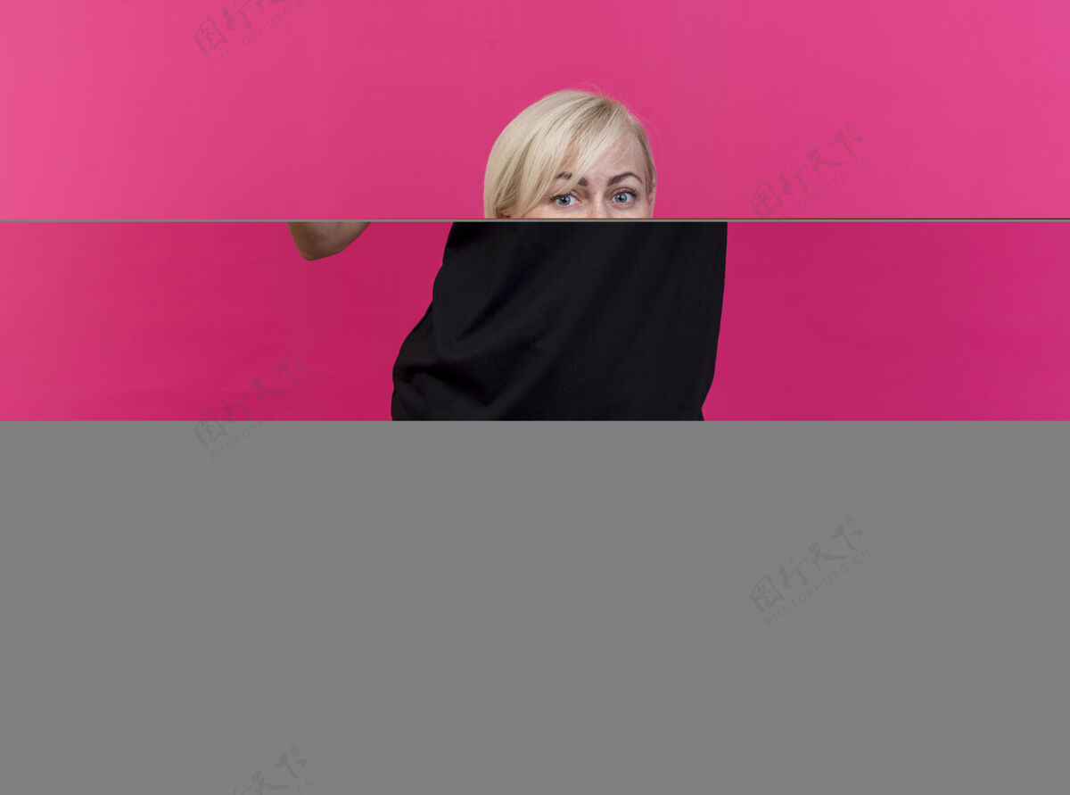 手机微笑着的中年金发斯拉夫女人展示着手机 指着隔离在深红色墙上的手机电话金发秀