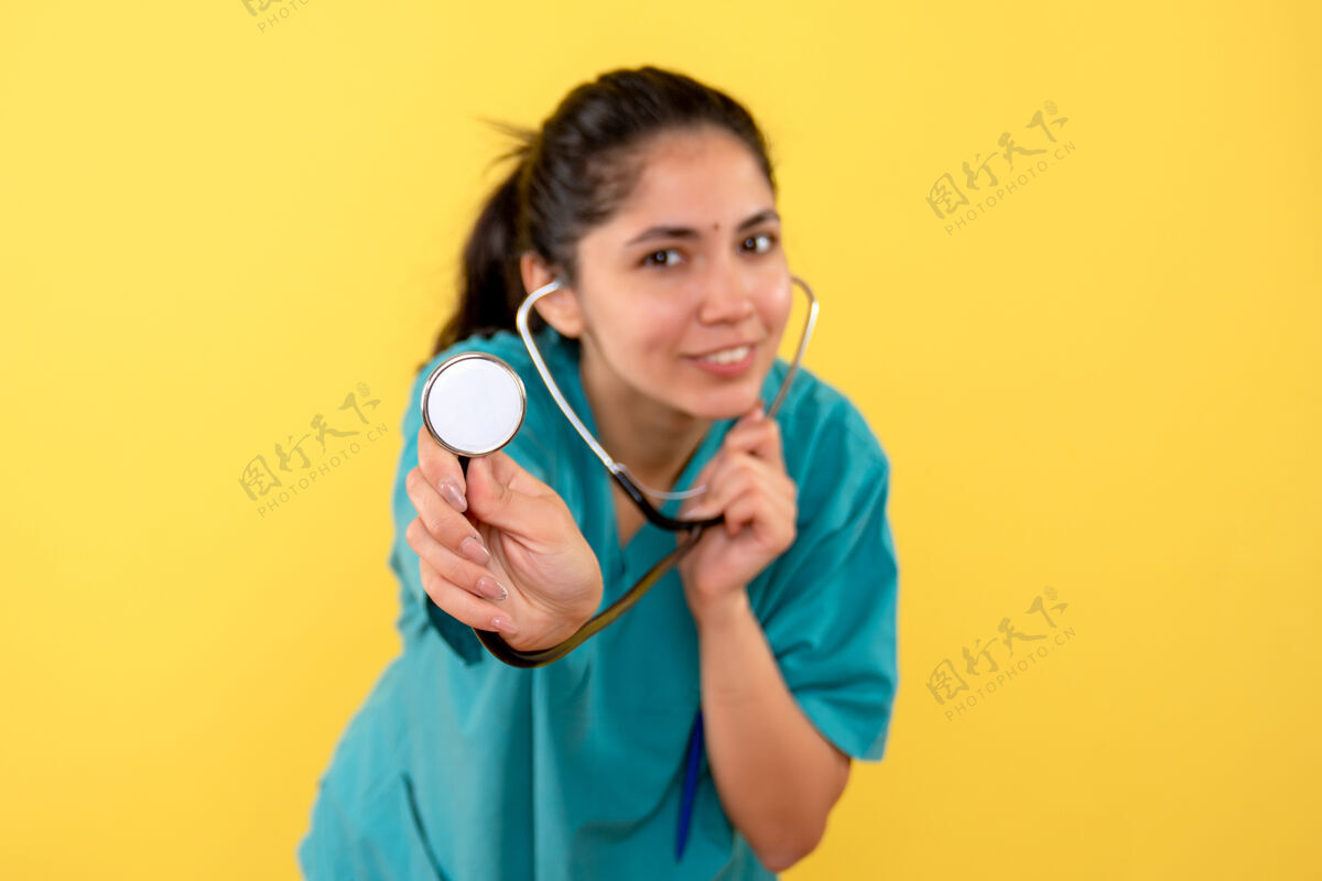 前面黄色隔离墙上女性手上听诊器的正视图微笑女成人
