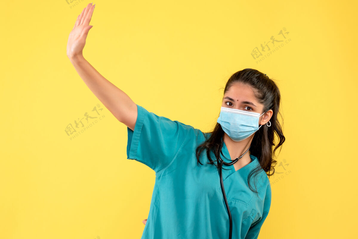 人身着制服的女医生正对着站在黄墙上的人打招呼肖像前面医疗