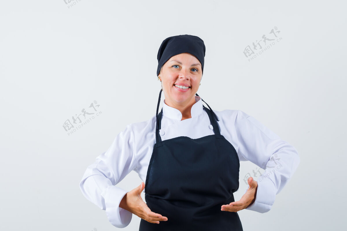 水疗穿着制服的女厨师 围着围裙假装举起或拿着什么东西 看上去很自信 正面照女性黑发模特