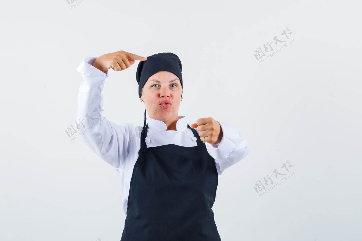 指点女厨师穿着制服 围裙指着摄像机 看上去很自信前视图制服健康皮肤护理