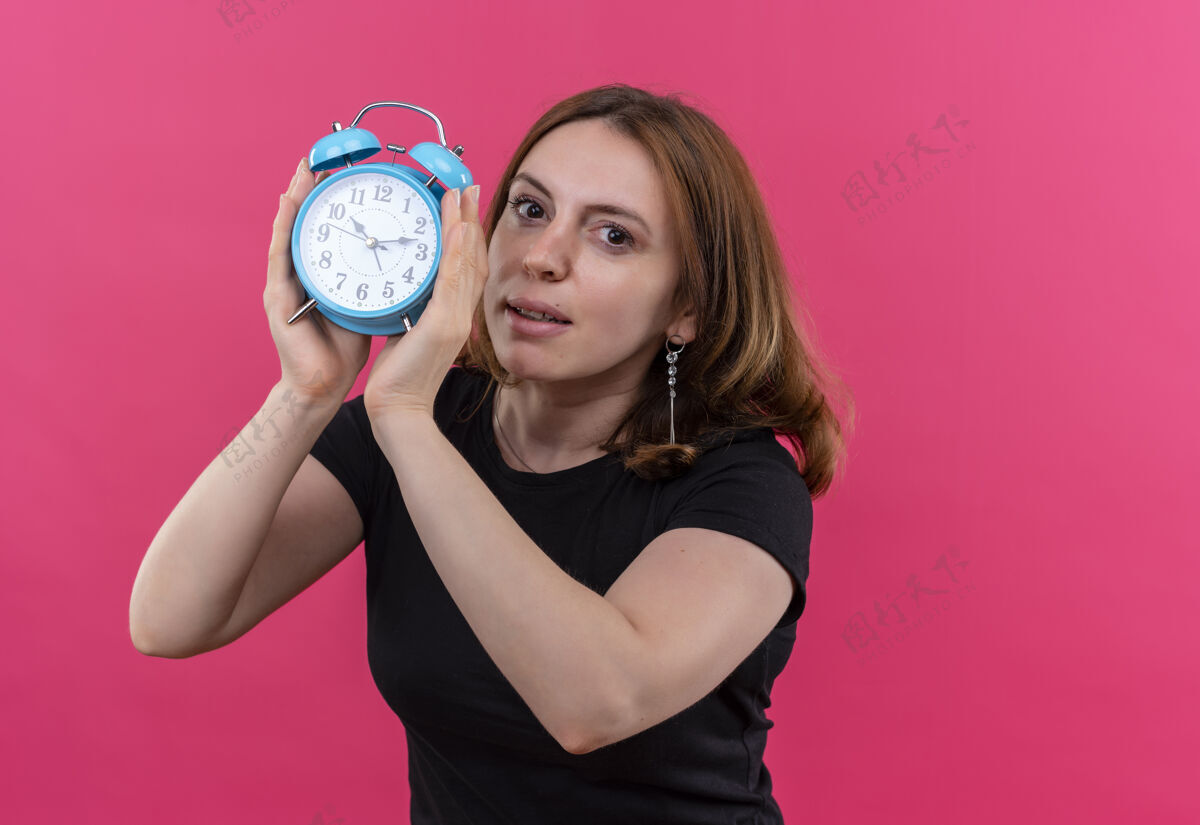 抱着年轻随意的女人拿着闹钟 站在隔离的粉色墙上 留着复印空间时钟闹钟年轻