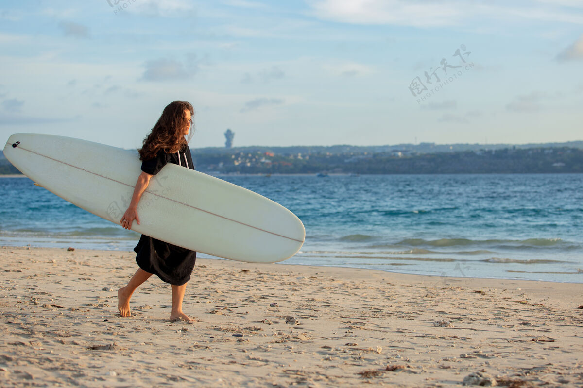 乐趣美丽的女孩拿着冲浪板站在沙滩上冲浪板冲浪者海洋