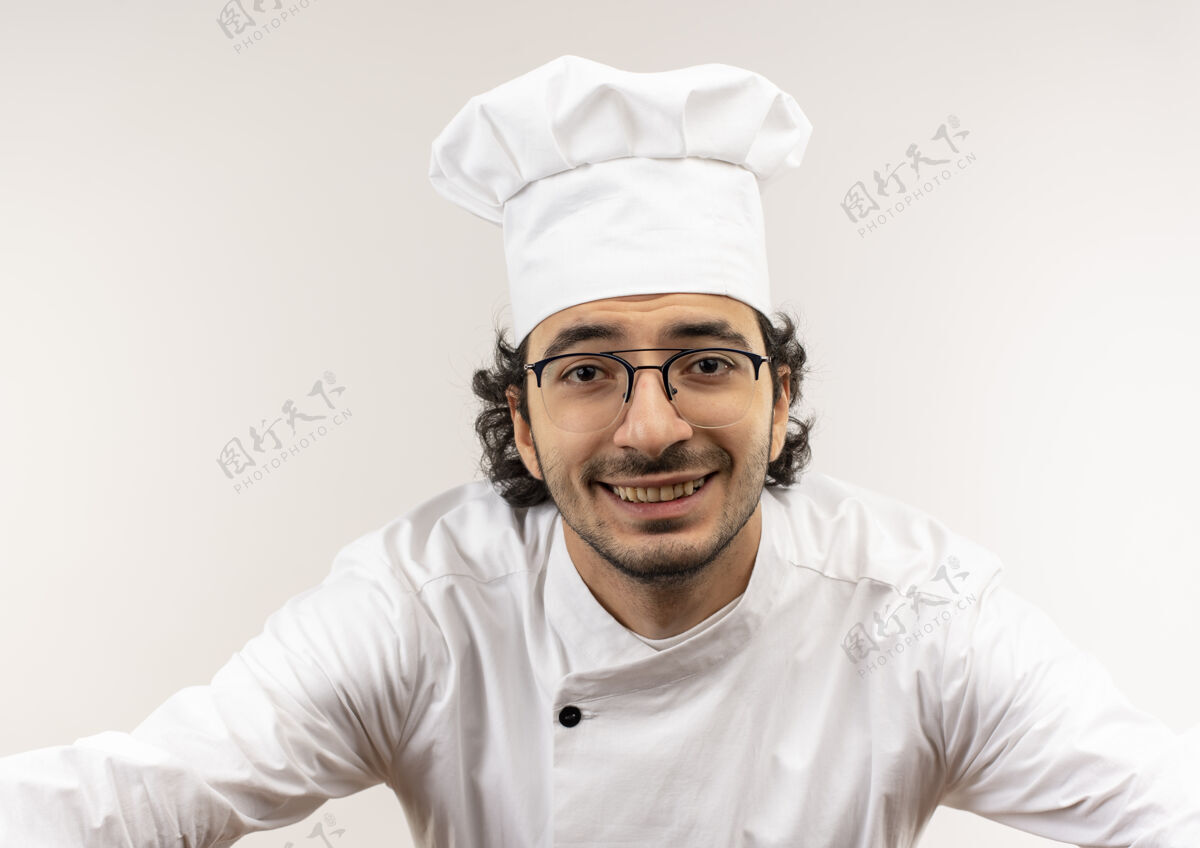 烹饪面带微笑的年轻男厨师穿着厨师制服 戴着眼镜 隔离在白色的墙上男眼镜戴着