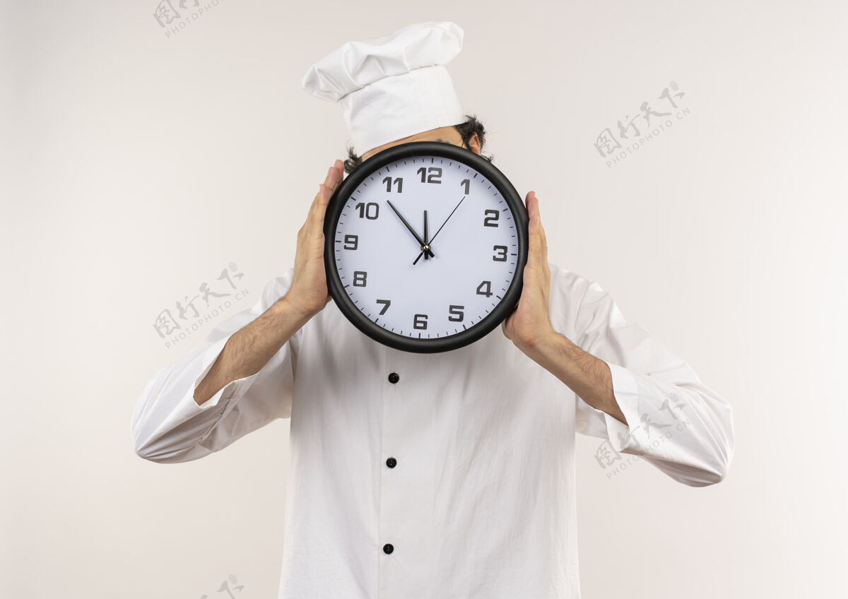 眼镜年轻的男厨师穿着厨师制服 戴着眼镜 脸上戴着隔离在白色墙上的挂钟年轻盖脸