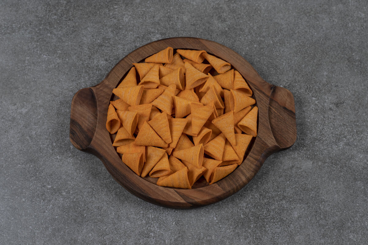 配料奶酪口味的锥形玉米片放在大理石表面的木制盘子里美味美味风味