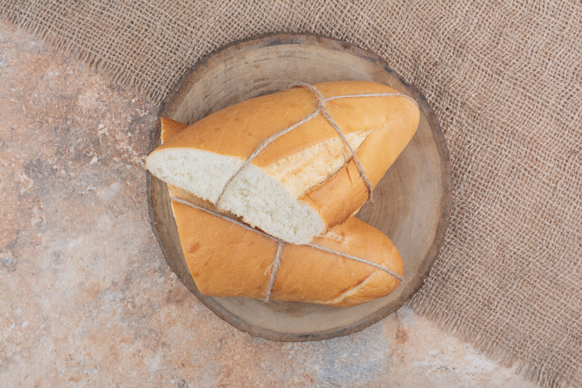 面包房用绳子绑在木板上的新鲜面包好吃的切的半块