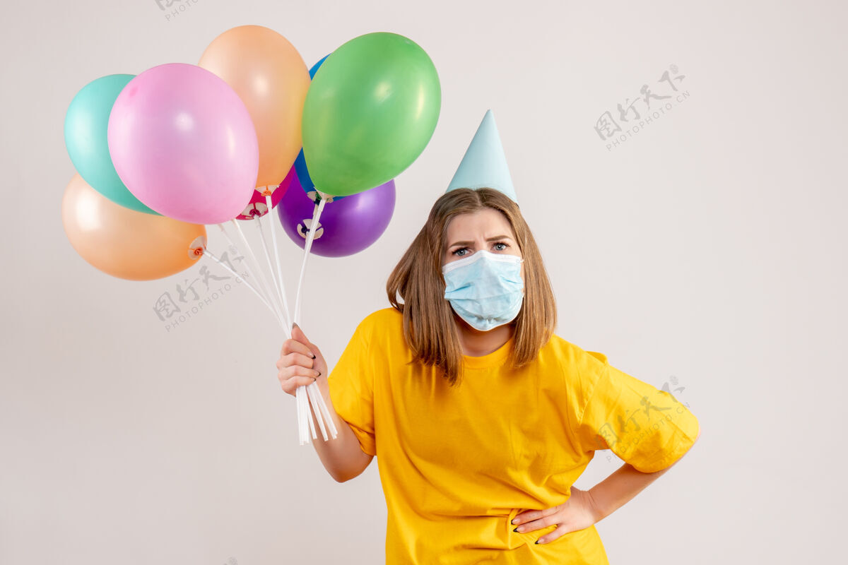 庆祝年轻的女性手持彩色气球 戴着白色的无菌口罩生日年轻女性聚会