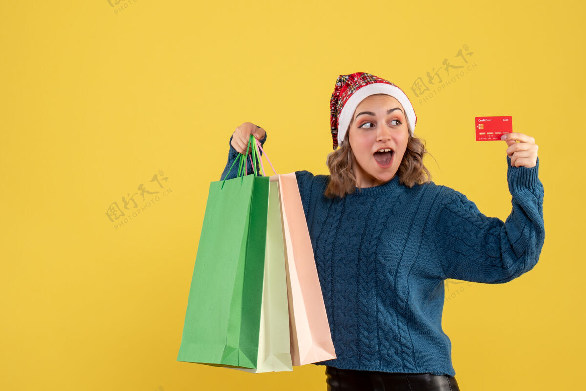 购物者年轻女子持银行卡和包裹购物后上黄色年轻女性购物女人