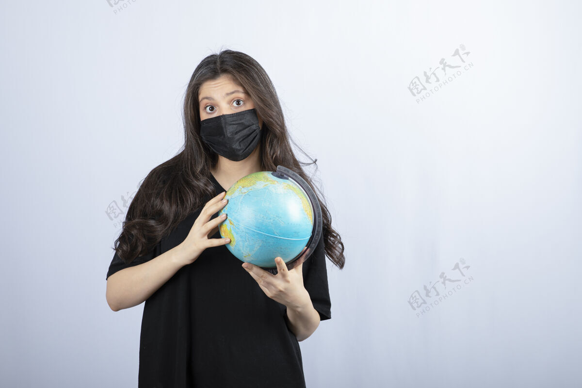 球戴着医用面具的黑发女人拿着世界地球仪女孩地球站立