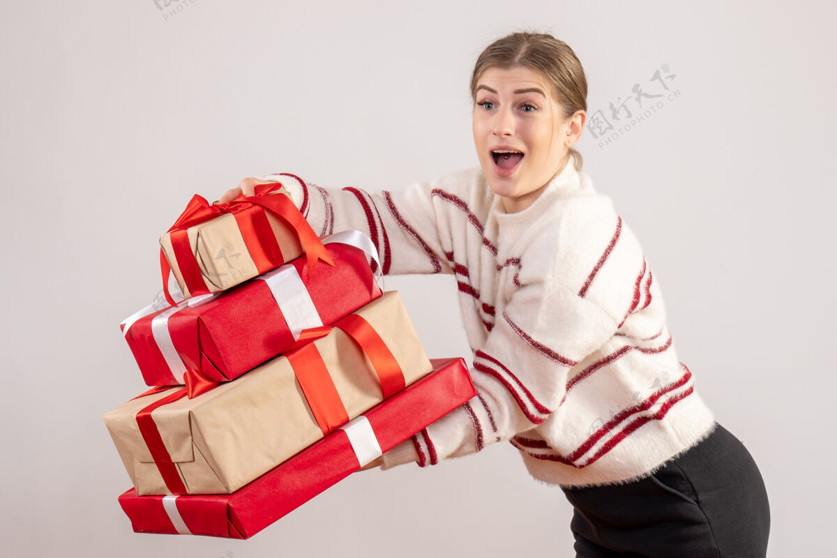 情感年轻的女性手持圣诞礼物在白色携带礼物观看