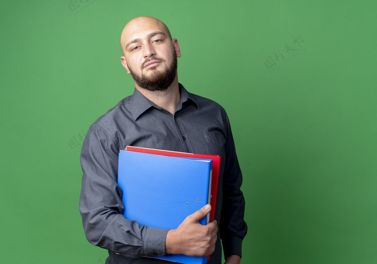 呼叫自信的年轻秃头呼叫中心男子拿着文件夹隔离在绿色与复制空间文件夹持有空间