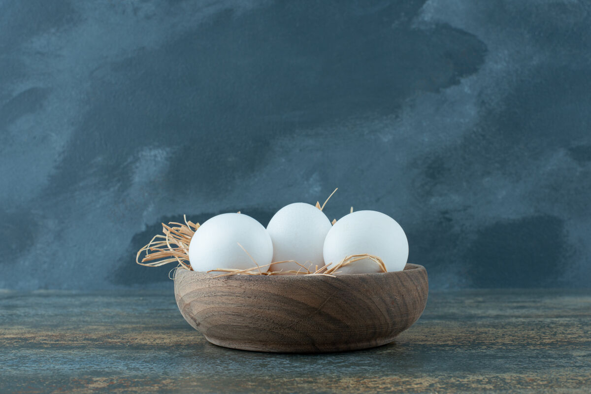 白新鲜的鸡蛋躺在干草木碗上食物家禽生的