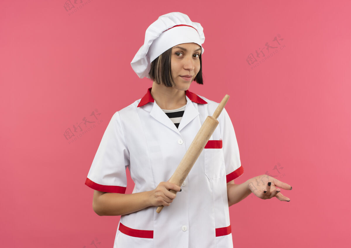 烹饪自信的年轻女厨师 身着厨师制服 手拿擀面杖 手上空空如也 粉红色 留有复印空间粉红信心空间