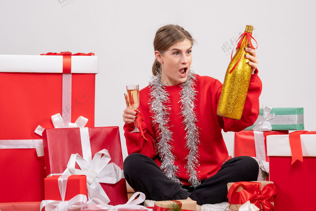 香槟漂亮的女人围坐在圣诞礼物旁 用白色香槟庆祝购物礼物礼物