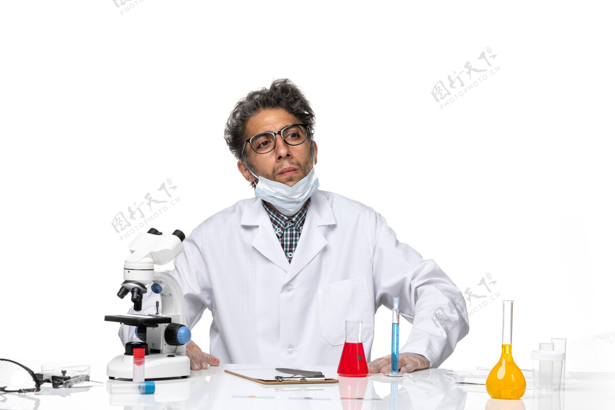 实验正面图穿着特殊白色西装的中年科学家围坐在桌子旁 拿着解决方案科学实验室外套科学