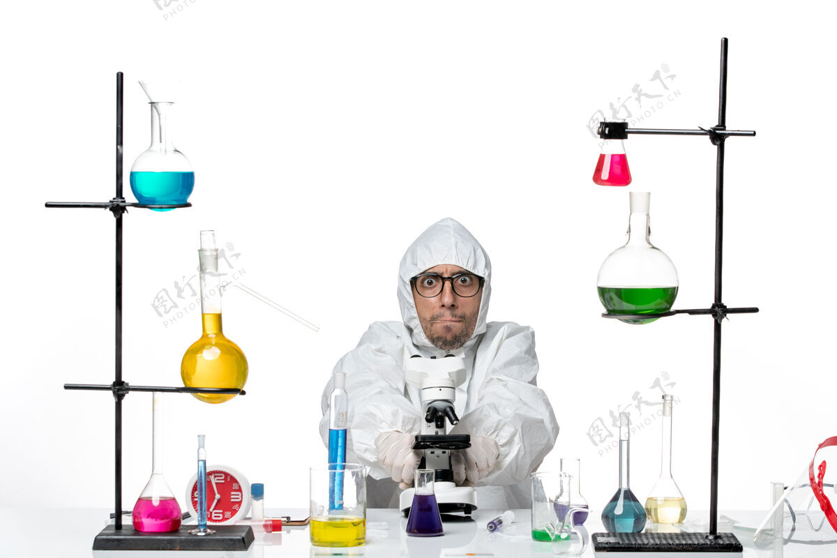 化学品正面图穿着特殊防护服的男科学家坐在那里解决问题容器罐子前面