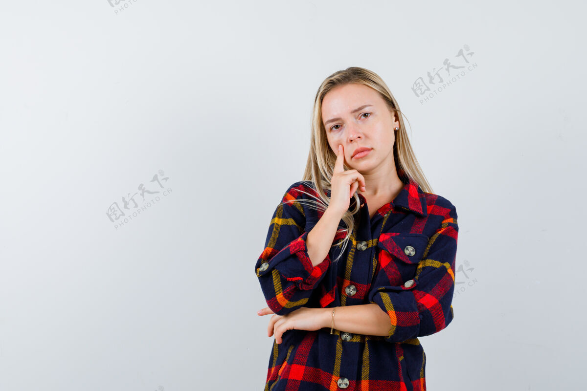 头部年轻女士穿着格子衬衫站在思考的姿势 看起来犹豫不决 正面视图时尚女性健康