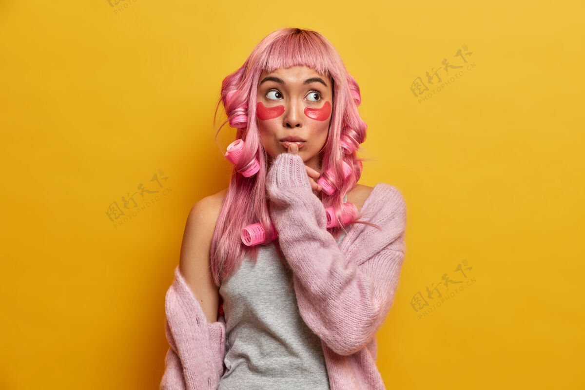 流苏体贴的亚洲女性 粉色头发 为特殊场合做准备 涂上胶原蛋白护垫和发卷 触摸嘴唇 集中在上面完美东方女士