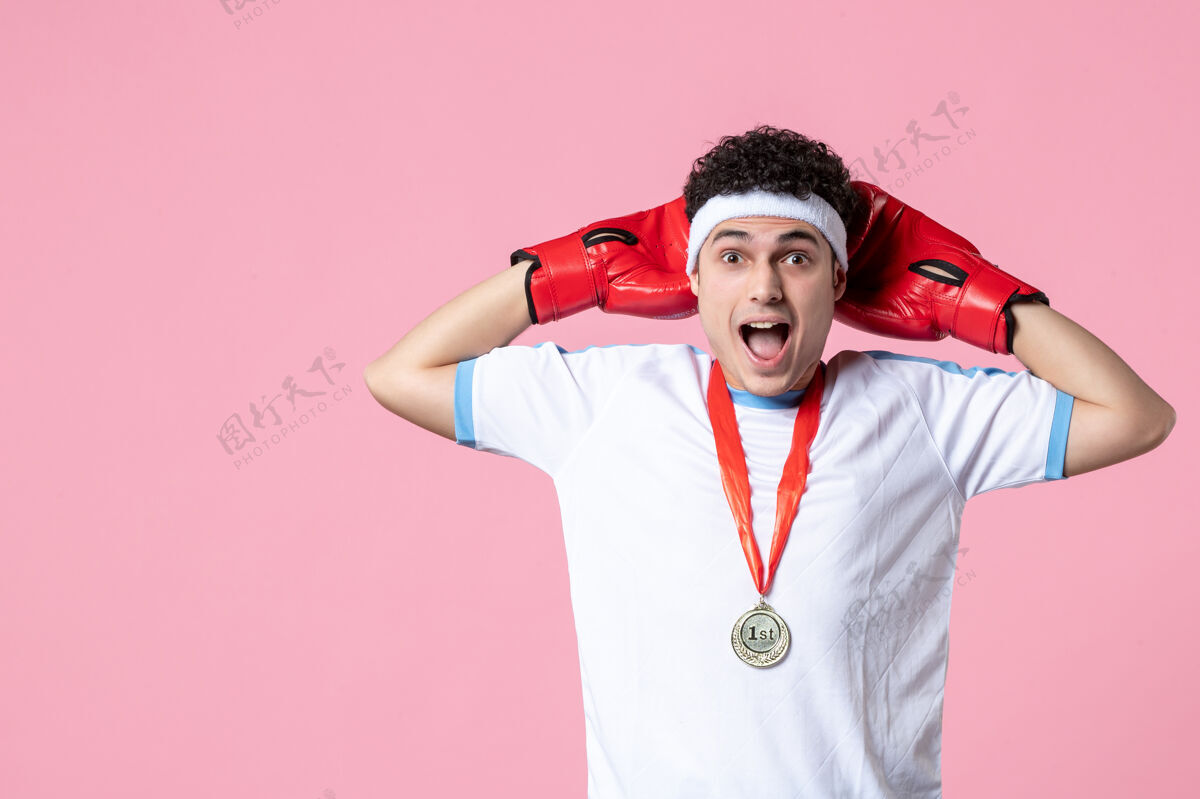 人正面图：年轻的男性拳击手穿着运动服站在粉红色的墙上运动年轻人惊喜